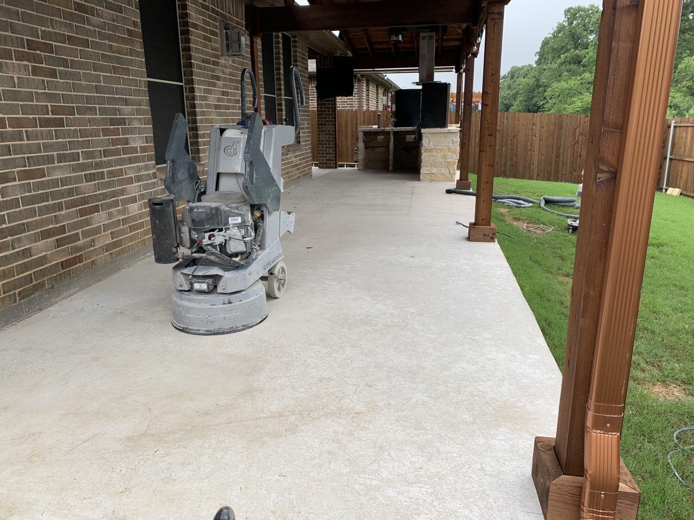 Crew grinding an outdoor concrete patio before coating